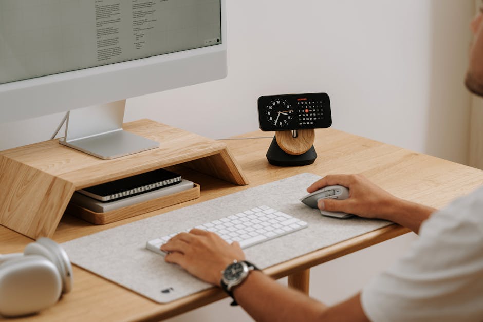 A clean and modern desk setup featuring a computer, clock, and accessories in a home office. — Photo by Mateusz Haberny